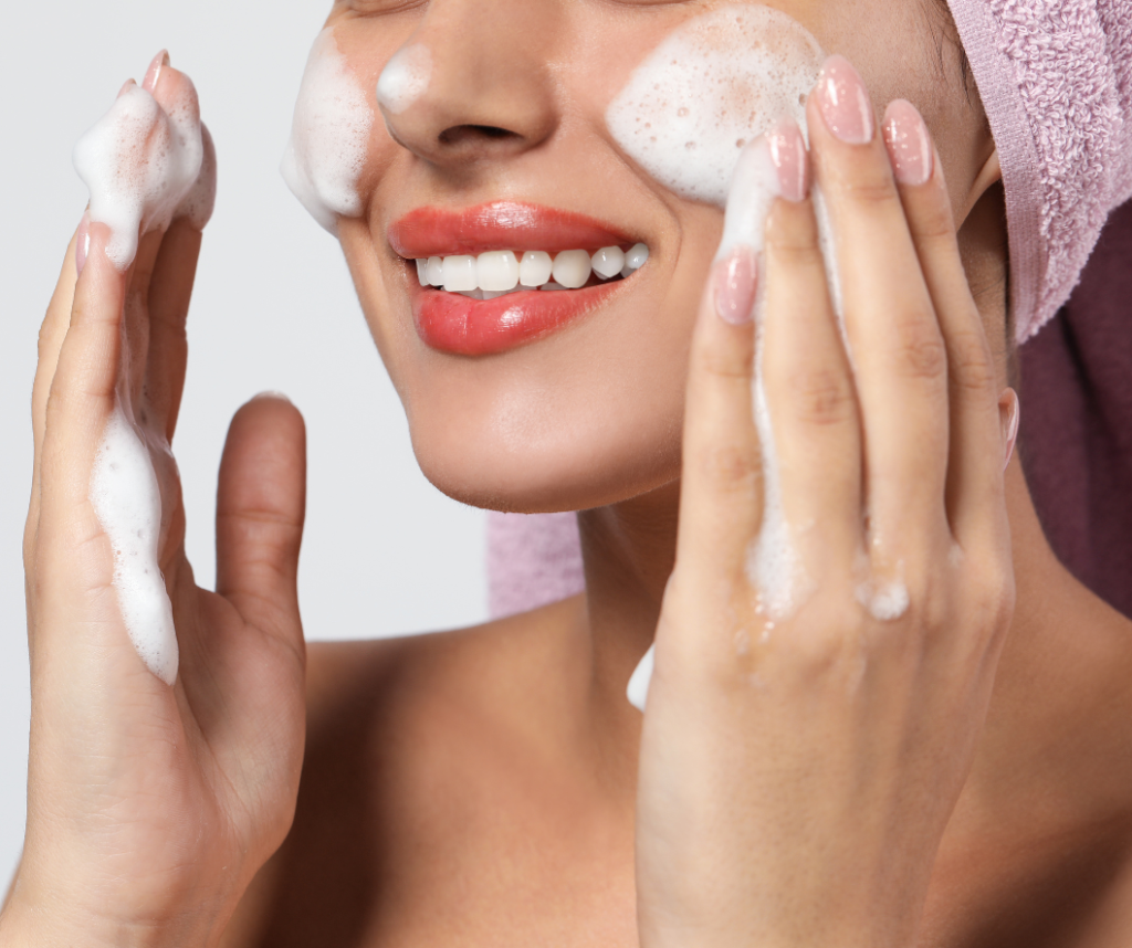 mujer sonriente con espuma en la cara haciendo su rutina de limpieza facial